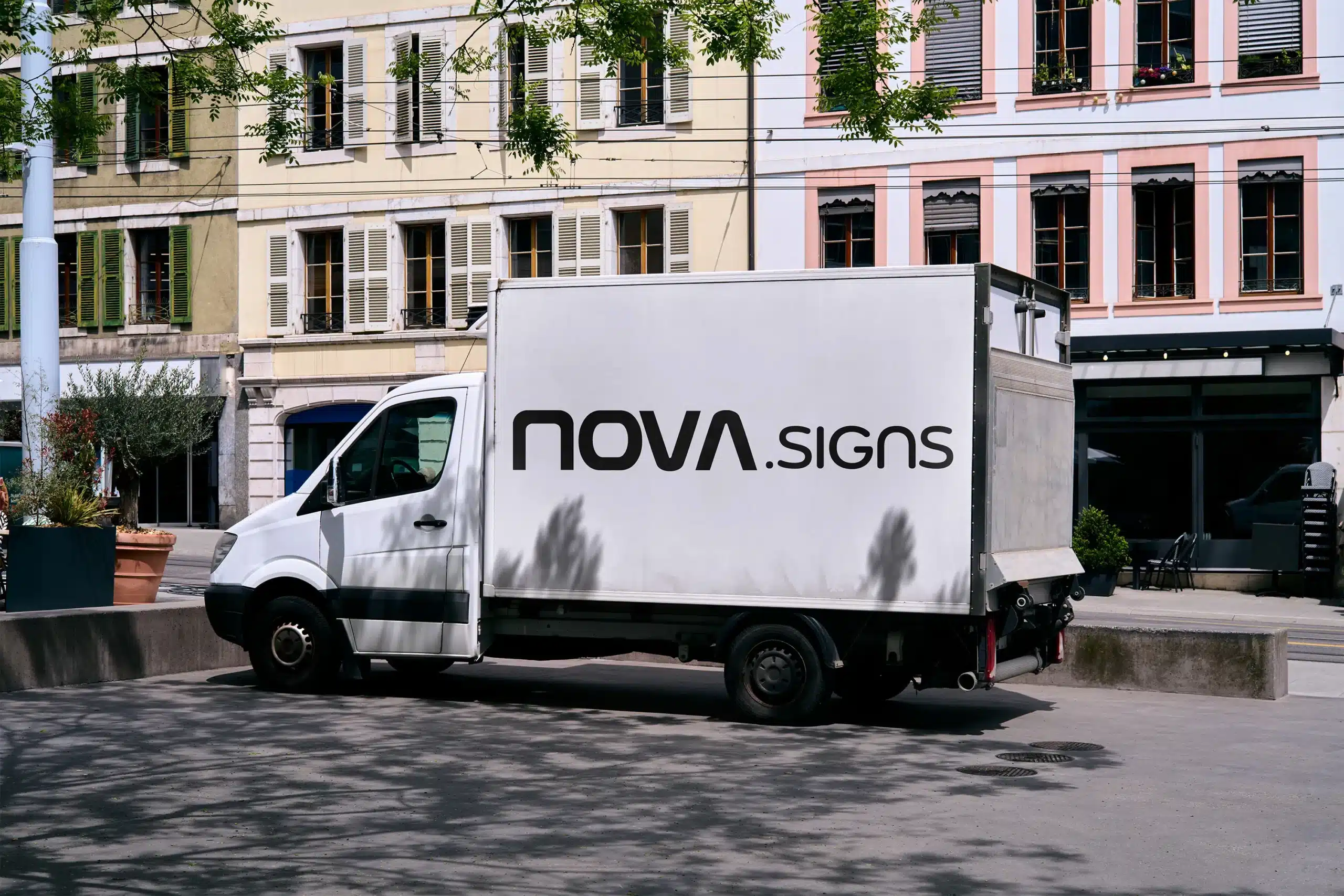 A white Nova Signs delivery van parked on the street, with a large black Nova Signs logo visible on the side.
